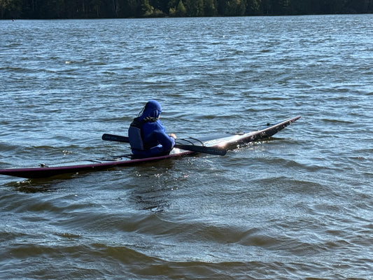Person in a kayak on a lake with trees in the background